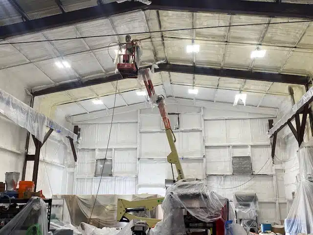 someone in a cherry picker inside a huge space that is being insultated